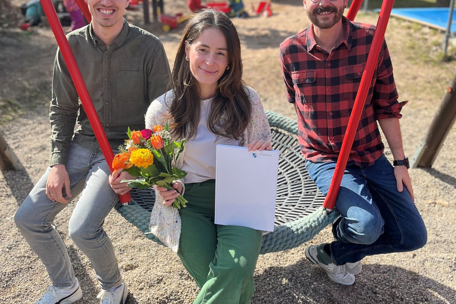 Mit einem bunten Frühlingsstrauß begrüßt Abteilungsleiter Rouven Rudisile (links) Frau Yildiz in der Gemeinde. Philipp Wöhr, Leiter der Kita Abenteuerland rechts im Bild.