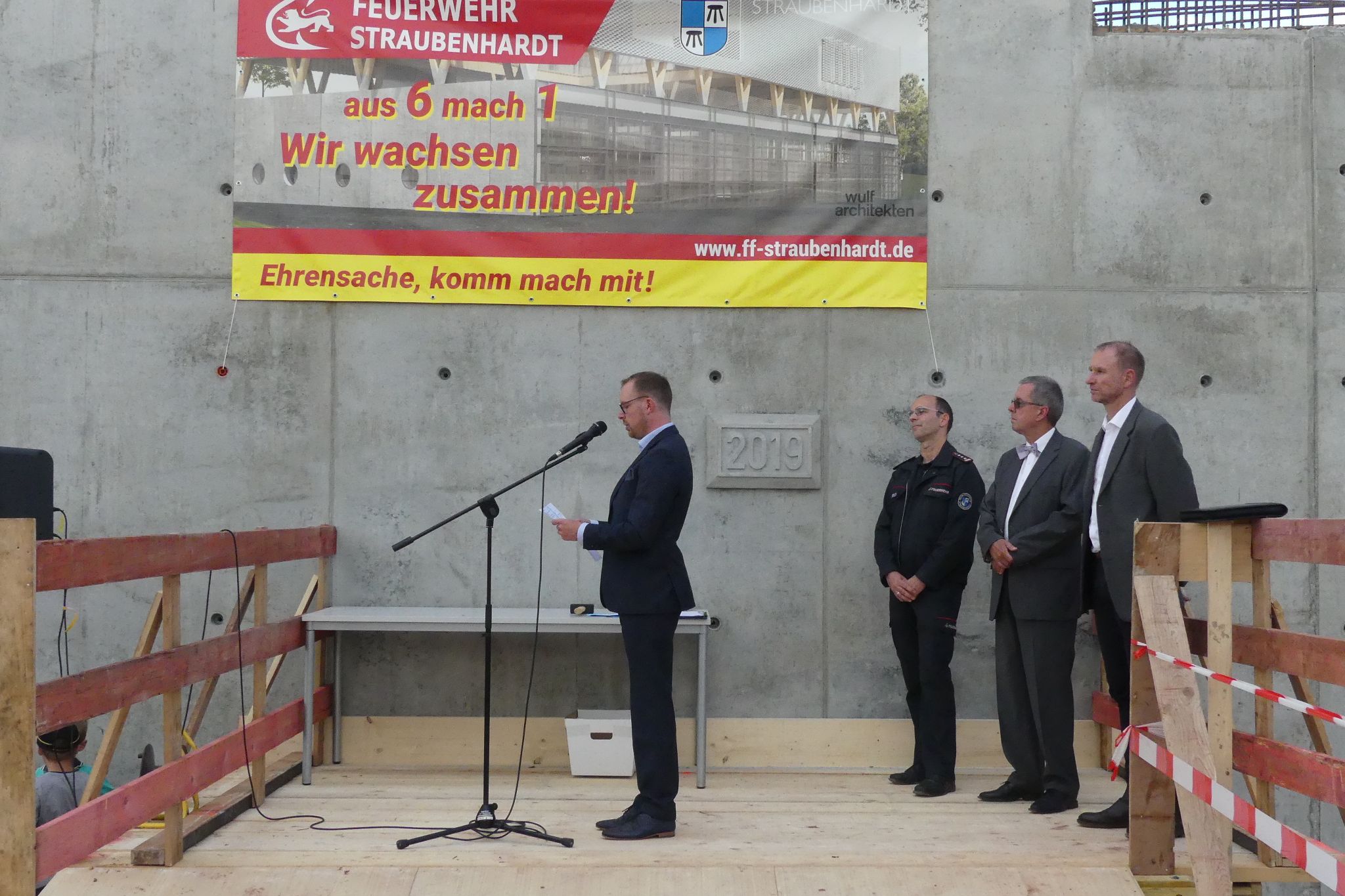 Bürgermeister Helge Viehweg (links) vor dem Grundstein, der eine Zeitkapsel für die Nachwelt abdeckt. Foto: Gemeinde